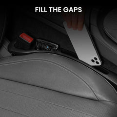 Black car seat gap filler catching a phone and car key beside a leather car seat.